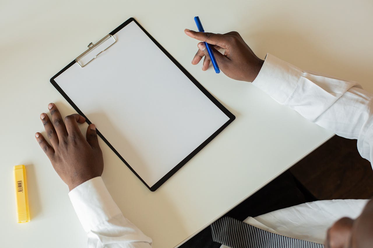 Overhead shot of a businessman with a clipboard and pen on a desk, ready to take notes.